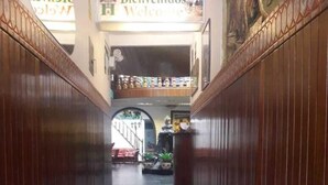 A hallway with a checkered floor, wooden paneling on the walls, and a 'Bienvenidos' sign. - Hostal Santa Apolonia (Cajamarca)