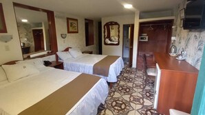 A hotel room with two beds, a small kitchenette, a mirror, and a television. - Hostal Santa Apolonia (Cajamarca)