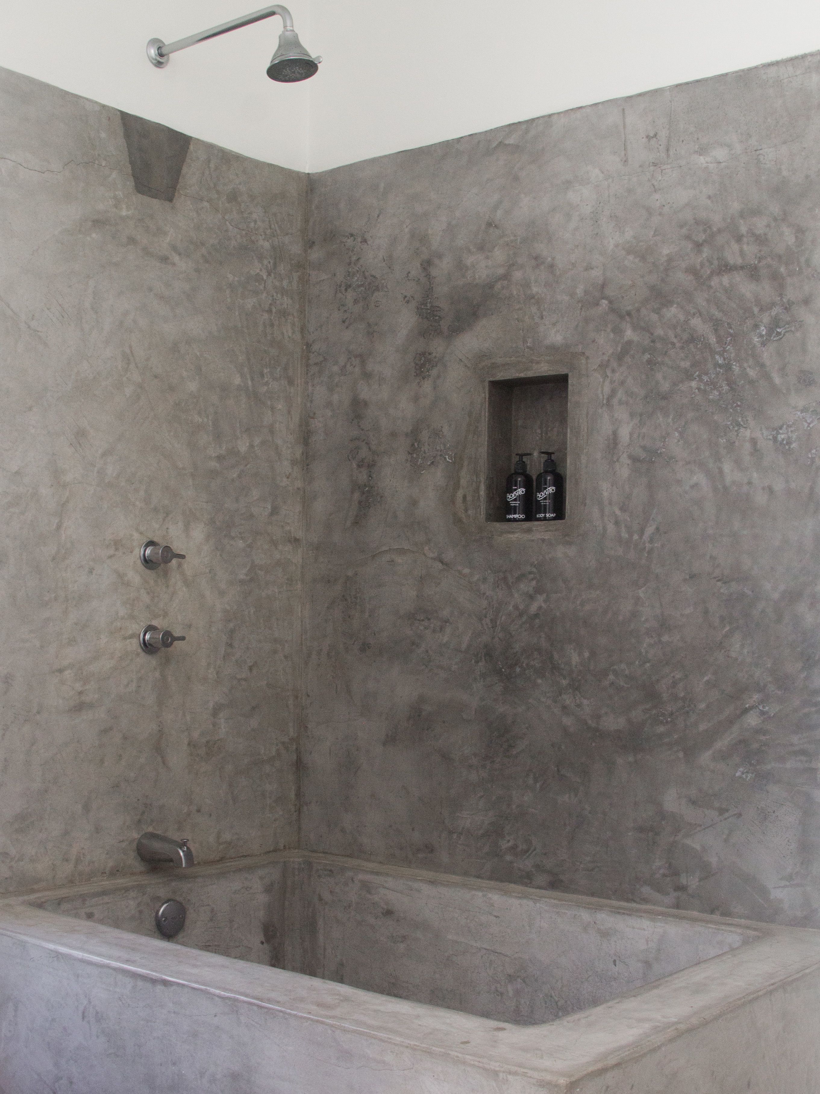 A bathroom with a bathtub, a showerhead, and a shelf with toiletries.