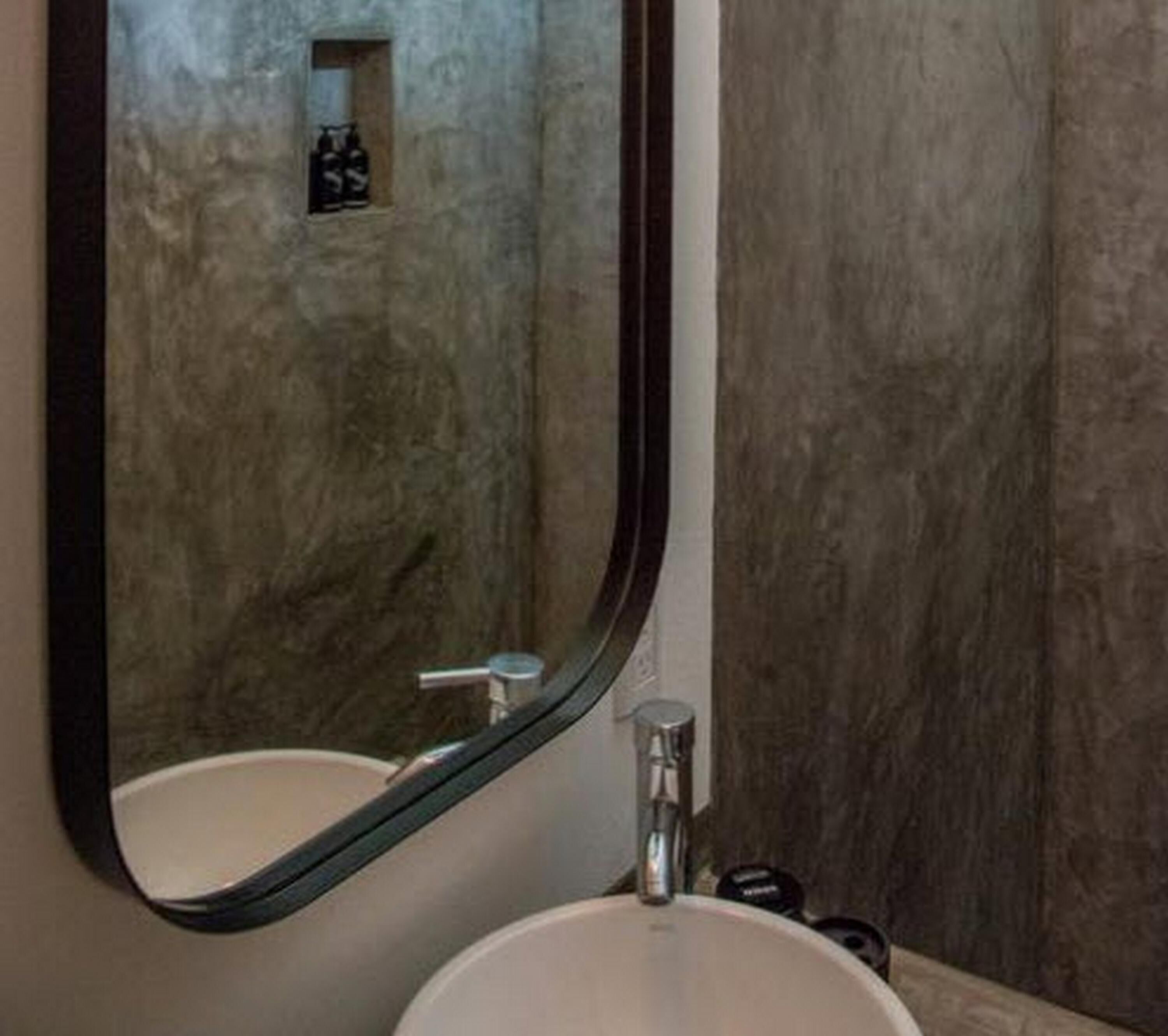 A bathroom with a large mirror, a sink, and a shower area.
