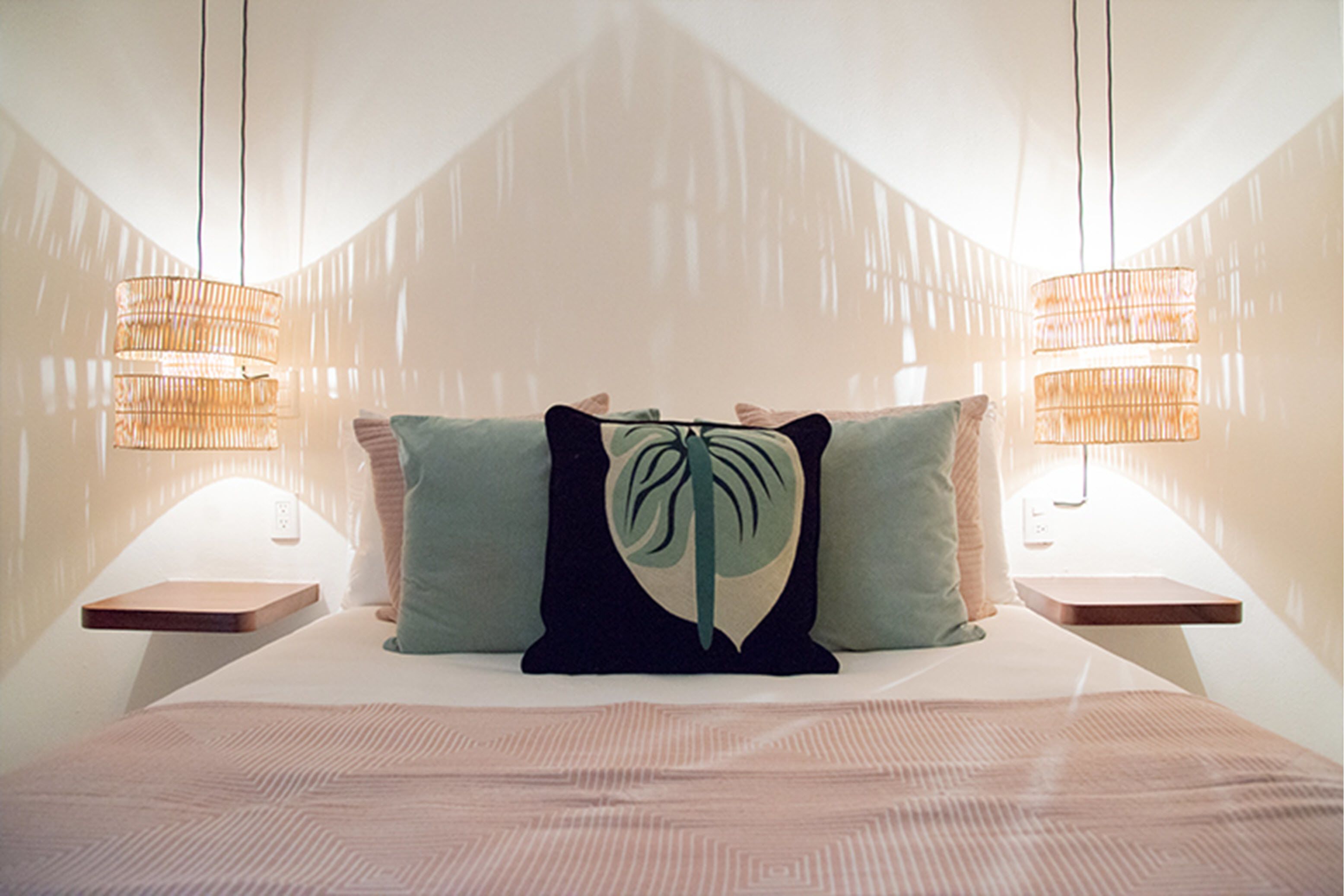 A bedroom with a bed, two bedside tables, and a hanging light fixture.
