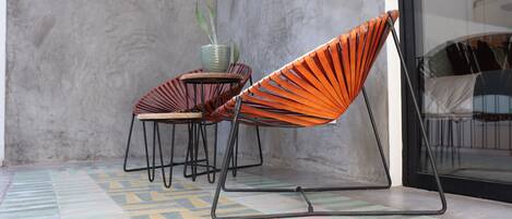 Un espacio al aire libre moderno con dos sillas y una mesa, una planta en maceta y un suelo con diseño.