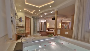 A modern bathroom with a large bathtub, a glass shower enclosure, and a vanity with a mirror. - Dolce Avita Hotel Spa & Resort (Andalo)