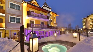 A hotel with a hot tub surrounded by snow, illuminated by purple and white lights. - Dolce Avita Hotel Spa & Resort (Andalo)