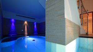 A modern indoor swimming pool with blue lighting and a glass wall. - Dolce Avita Hotel Spa & Resort (Andalo)