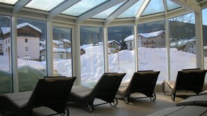 A sunroom with large windows overlooking a snowy landscape. - Dolce Avita Hotel Spa & Resort (Andalo)