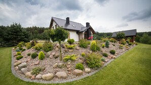 A modern house with a stone garden, a red chair outside, and a clear sky. - Dom nad jeziorem (gmina Rogowo)