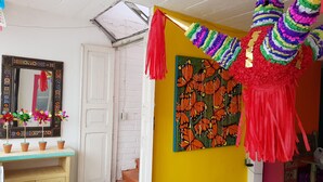 A room with a white door, a yellow wall, a colorful mural, and a decorative piñata. - Hostel Vallarta - Adults only (Puerto Vallarta)