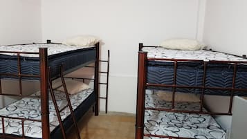 Una habitación con dos literas, cada una con colchón y almohada, y una escalera de madera.