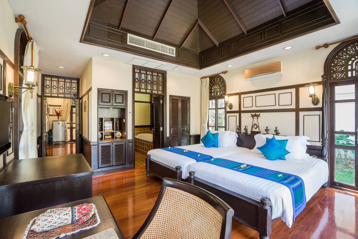 A hotel room with a large bed, a desk, a chair, and a view of the outdoors.
