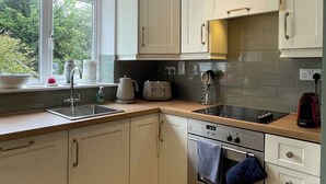 A kitchen with white cabinets, a window with a view, a sink, a stove, and a countertop with various appliances.