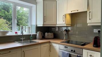 A kitchen with white cabinets, a window with a view, a sink, a stove, and a countertop with various appliances.