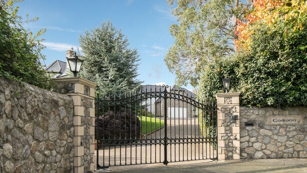 A gated entrance with a stone wall and a metal gate.