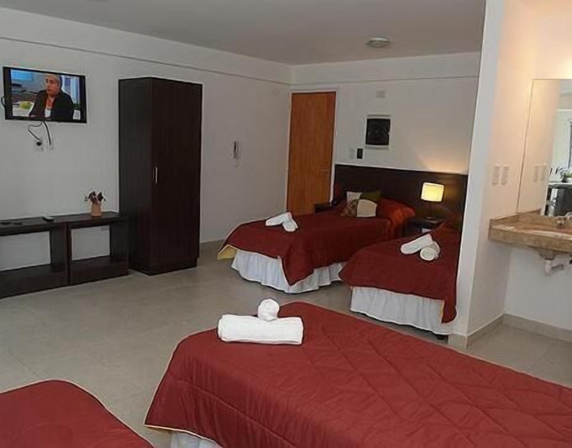 A hotel room with two beds, a TV, a wardrobe, and a bathroom.