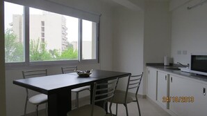 Una cocina moderna con comedor, ventanas amplias y vistas a edificios.
