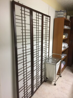 Traditional Japanese-inspired room with a shoji screen divider, wooden wardrobe, and metal storage cart.