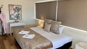 Ein ordentlich eingerichtetes Schlafzimmer mit Bett, Nachttisch und einem Bild an der Wand.