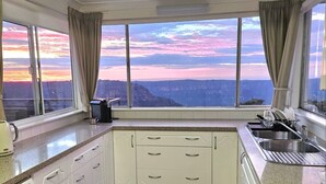 Eine Küche mit einem großen Fenster und Blick auf eine Schlucht bei Sonnenuntergang.