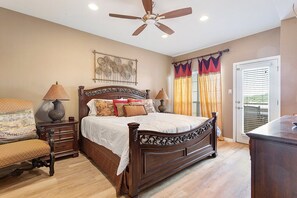 A bedroom with a large bed, two bedside tables, a ceiling fan, and a window with curtains.