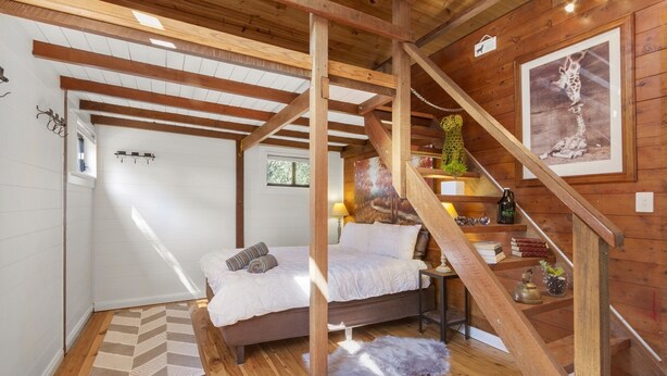 A cozy bedroom with a bed, a small table, a lamp, and a staircase leading to another level. - BLUE APPLE LODGE - a fabulous mountain holiday escape! SPECIALS ON NOW ! (Bilpin)