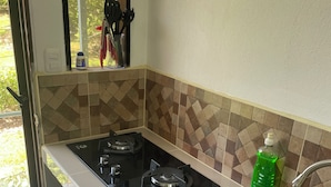 A kitchen with a gas stove, stainless steel sink, and tiled backsplash.