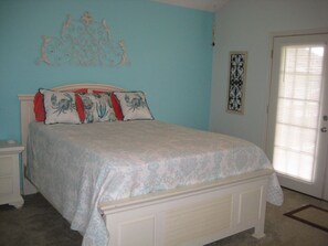 A bedroom with a bed, a nightstand, a decorative wall piece, and a door with a window. - Quiet Bay House Retreat With Easy Access, Great View. (Port O'Conner)