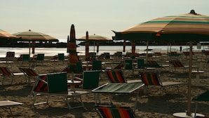 Een strand met rijen gestreepte ligbedden en parasols.
