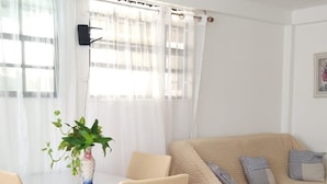 Ein Essbereich mit einem runden Tisch, Stühlen, einer Couch und Blumentöpfen.