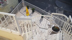 A marble staircase with white railings, a potted plant with marigolds, and a yellow umbrella on the balcony. - AL Santa Marta de Penaguião (Santa Marta de Penaguião)