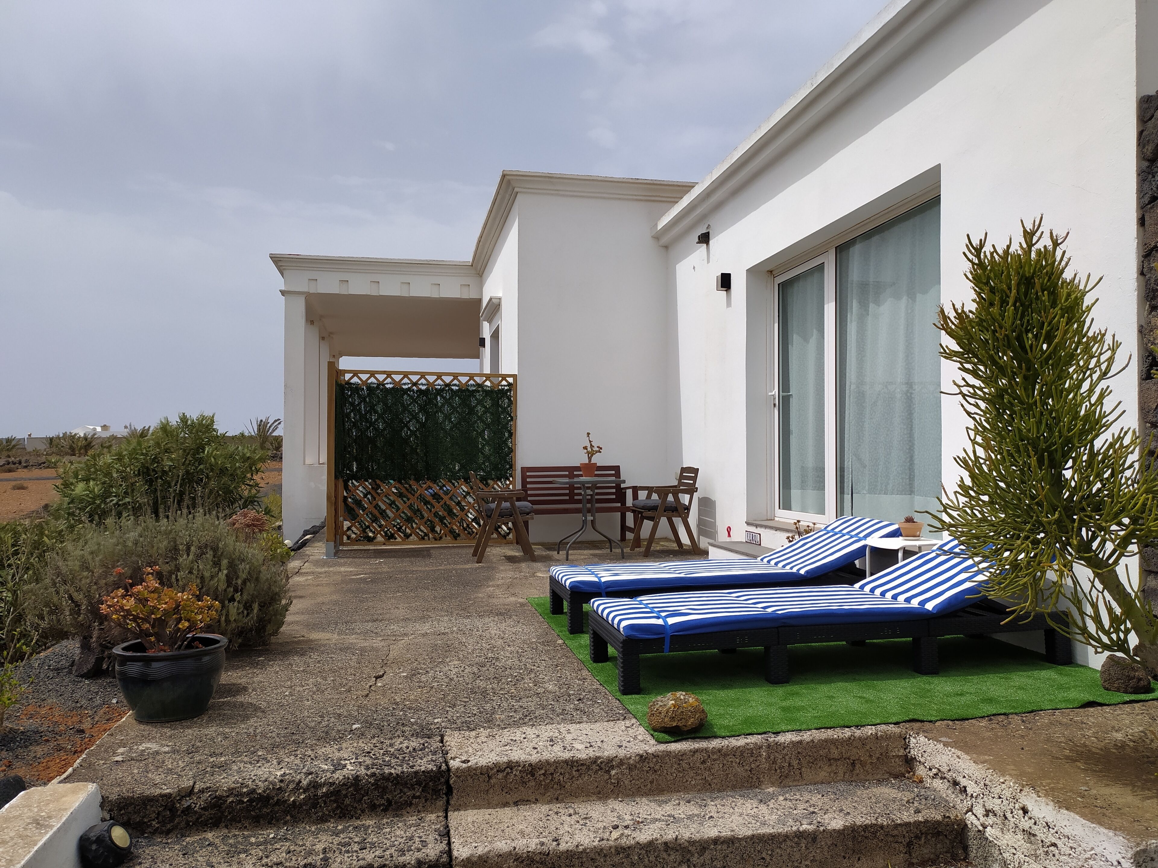 Un espace de détente extérieur moderne, comprenant deux chaises longues, une petite table et des chaises.