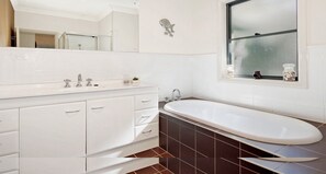 A modern bathroom with a freestanding bathtub, a large mirror, and a window with a view of the outside.