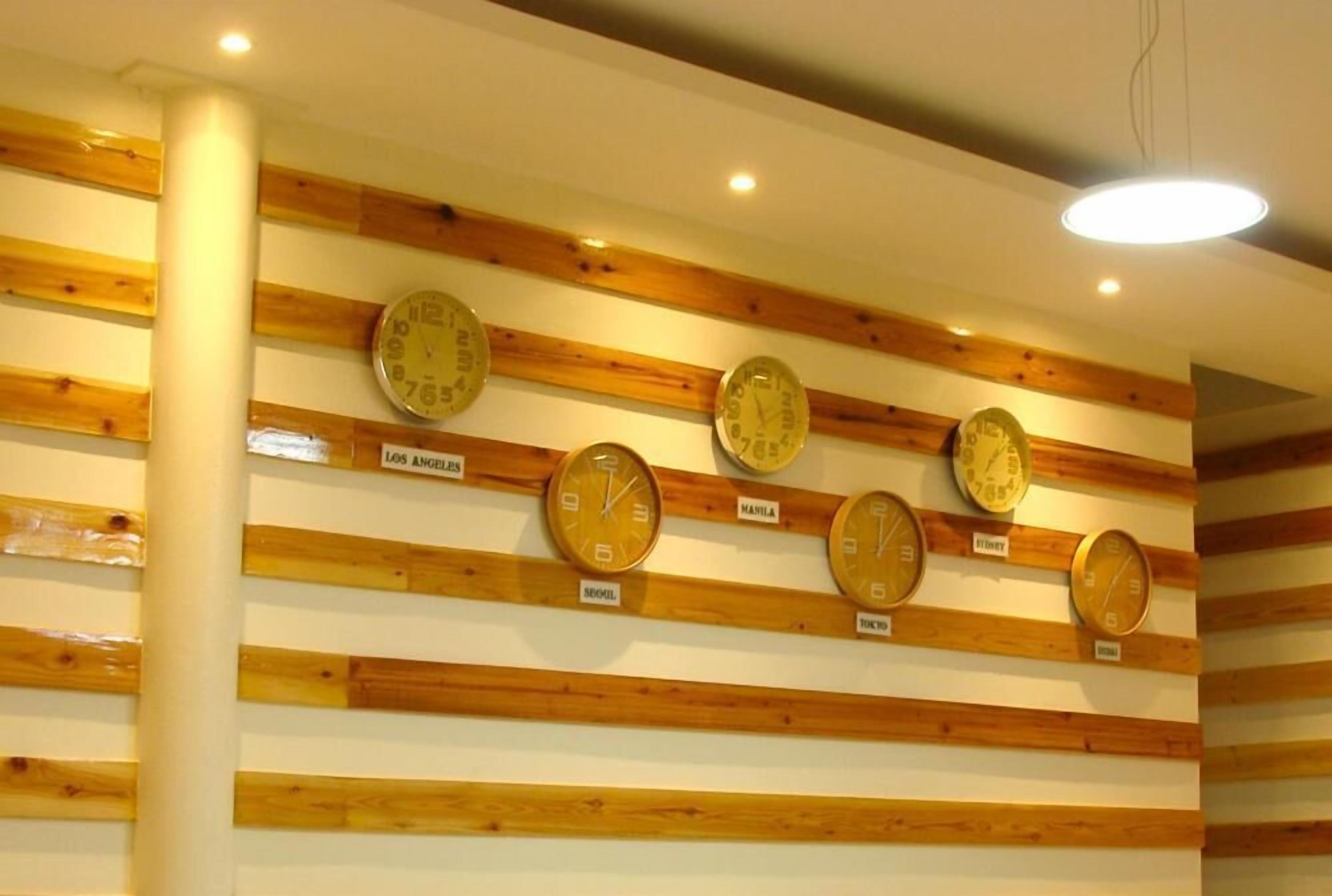 Eine Wand mit Uhren, die mit Städtenamen wie Los Angeles, Manila und Tokio beschriftet sind.