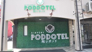 The exterior of the Airport Poddotel with a green wall and a sign displaying the hotel's name in both English and Japanese. - Airport Poddotel (Pasay)