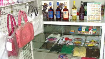 Exposição de produtos de venda ao público, com bolsas, bebidas alcoólicas e produtos embalados.