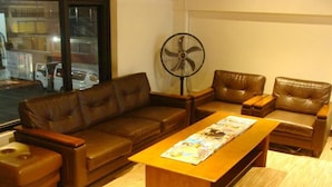 A living room with a brown leather sofa, a wooden coffee table, and a floor lamp. - Airport Poddotel (Pasay)