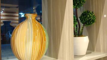 A shelf with a vase and two potted plants.