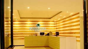 A reception area with a wooden slat wall, a green reception desk, and a white counter. - Airport Poddotel (Pasay)