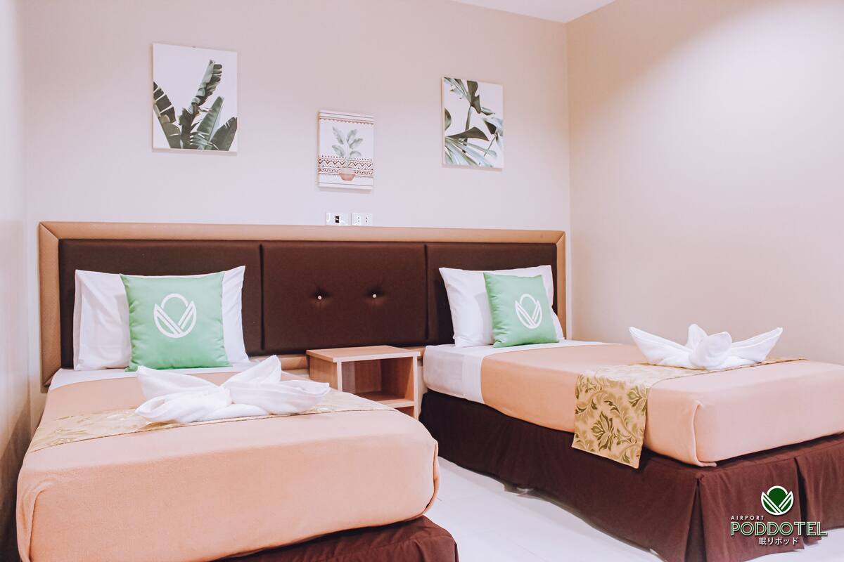 A hotel room with two beds, a wooden headboard, and artwork on the walls.