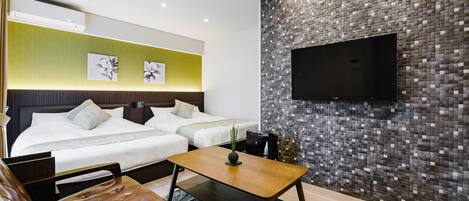 A modern hotel room with two beds, a flat-screen TV mounted on a mosaic wall, a wooden coffee table, and a leather sofa.