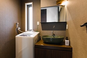 A compact bathroom with a built-in washing machine, a green sink, and a mirror above it. - HOTEL -sui- HARUYOSHI (Fukuoka)
