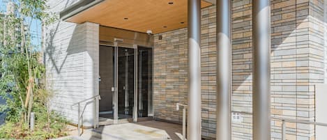 A modern building entrance with a covered area, glass doors, and a stone facade.