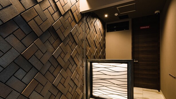 A modern hallway with a patterned wall, a framed artwork, and a door with a sign. - HOTEL -sui- HARUYOSHI (Fukuoka)