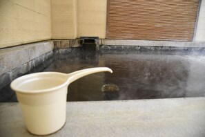 A hot spring bath with a wooden bench and a beige bucket. - Kumamoto Capsule Hotel - Hostel, Caters to Men (Kumamoto)