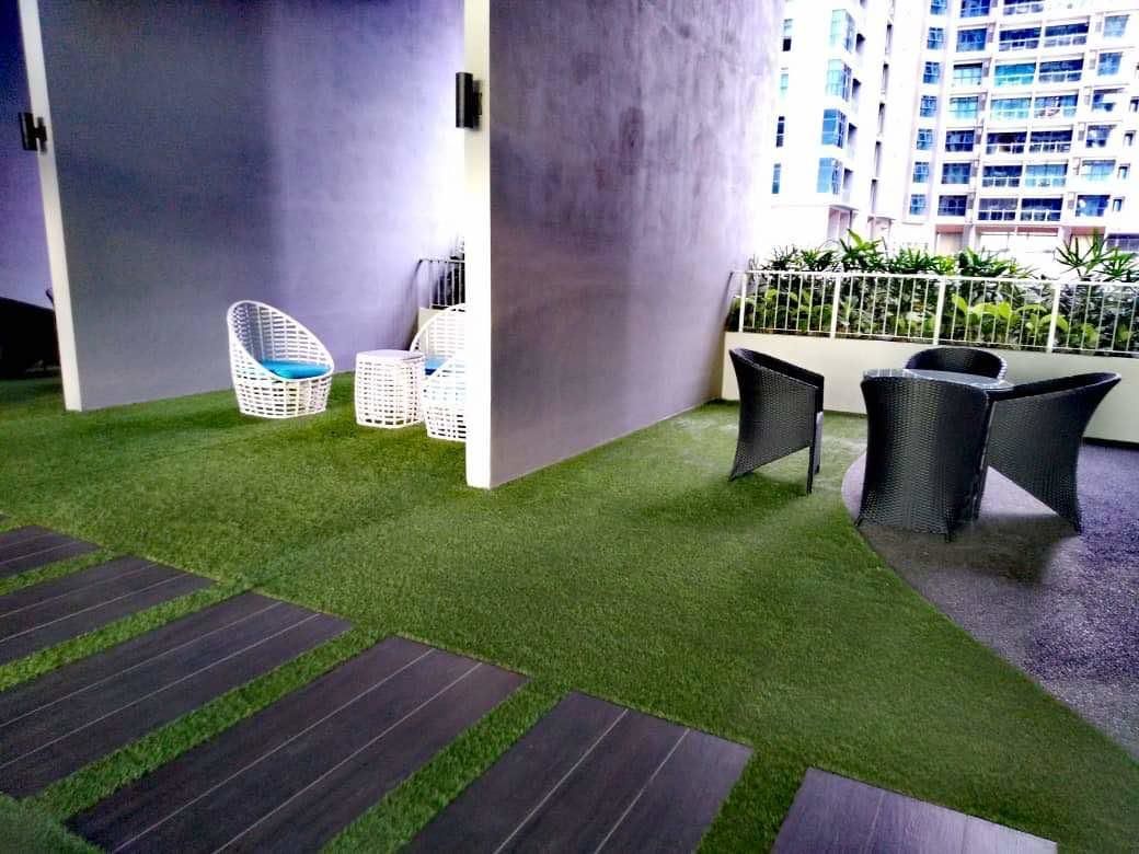 Una terraza en la azotea con césped artificial, mobiliario de mimbre y vistas a un rascacielos.