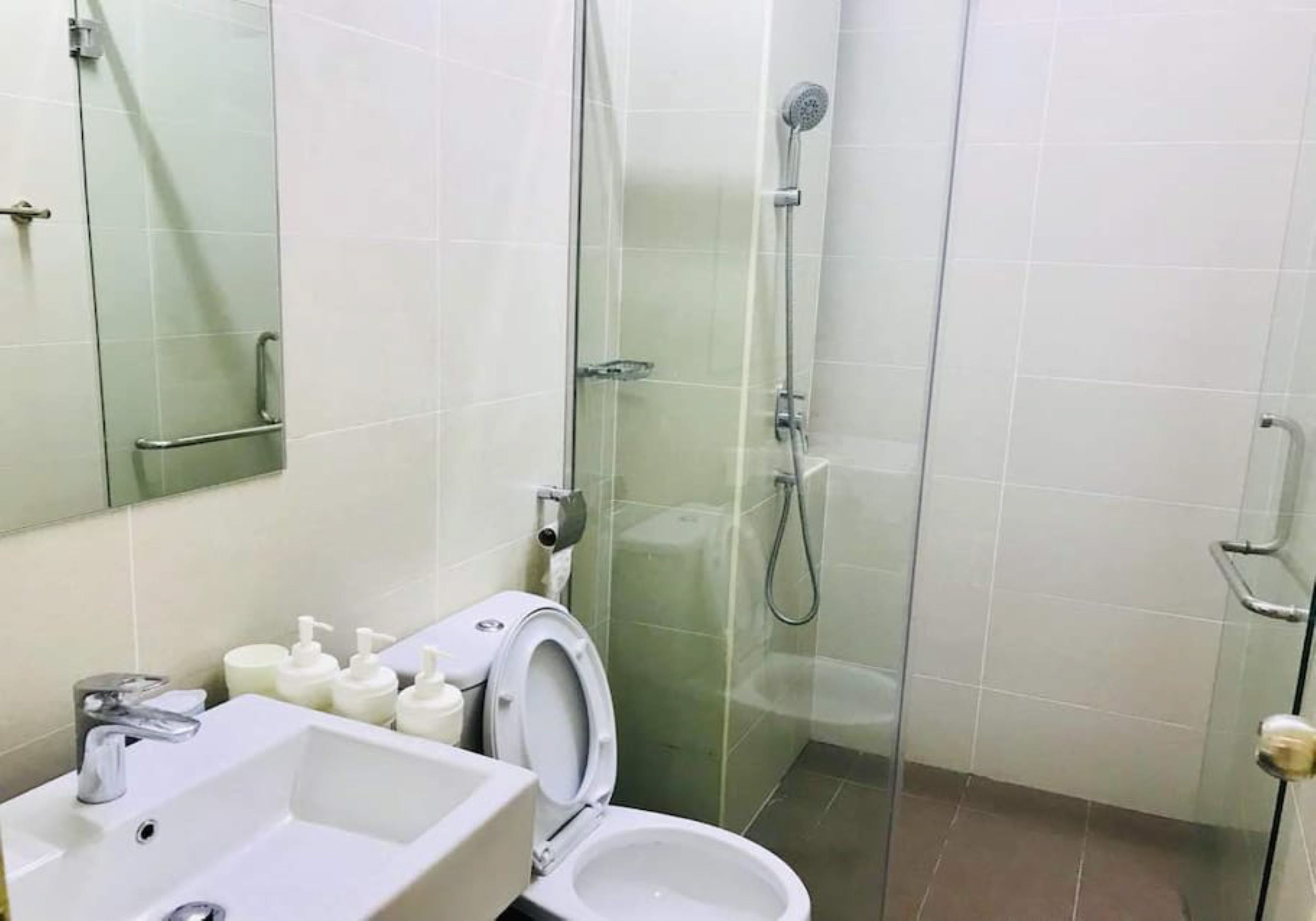 A bathroom with a glass-enclosed shower, a white sink, and a toilet.