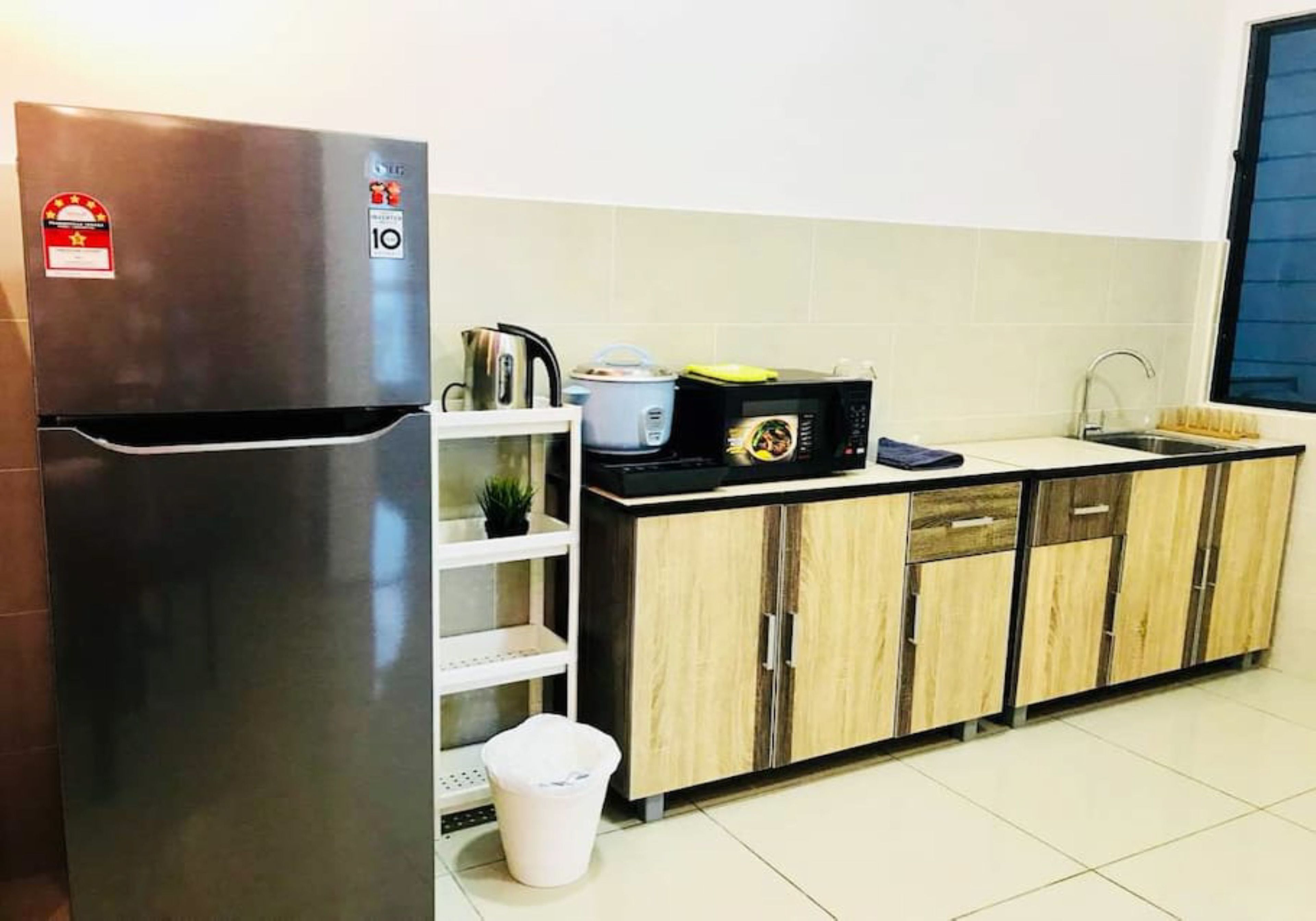 A kitchen with a stainless steel refrigerator, a microwave, a sink, and wooden cabinets.
