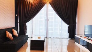 Ein modernes Wohnzimmer mit einer schwarzen Couch, einem Flachbildfernseher und einem großen Fenster mit Vorhängen.