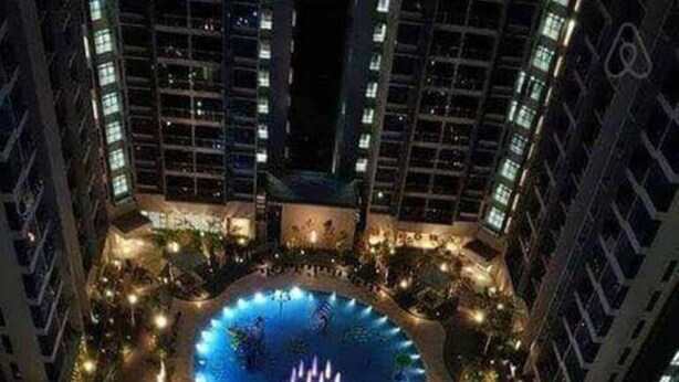 Ein großer, beleuchteter Pool, umgeben von hohen Gebäuden bei Nacht.