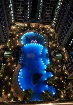 A large, illuminated swimming pool surrounded by high-rise buildings at night. - Atlantis Apple Home Melaka Town Area (Malacca City)
