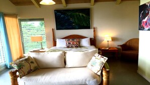 Ein Schlafzimmer mit Bett, Stuhl, Nachttisch, Lampe und einem Bild an der Wand.